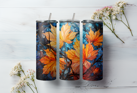 Three tumblers with autumn leaf design on a white wooden surface with flowers.